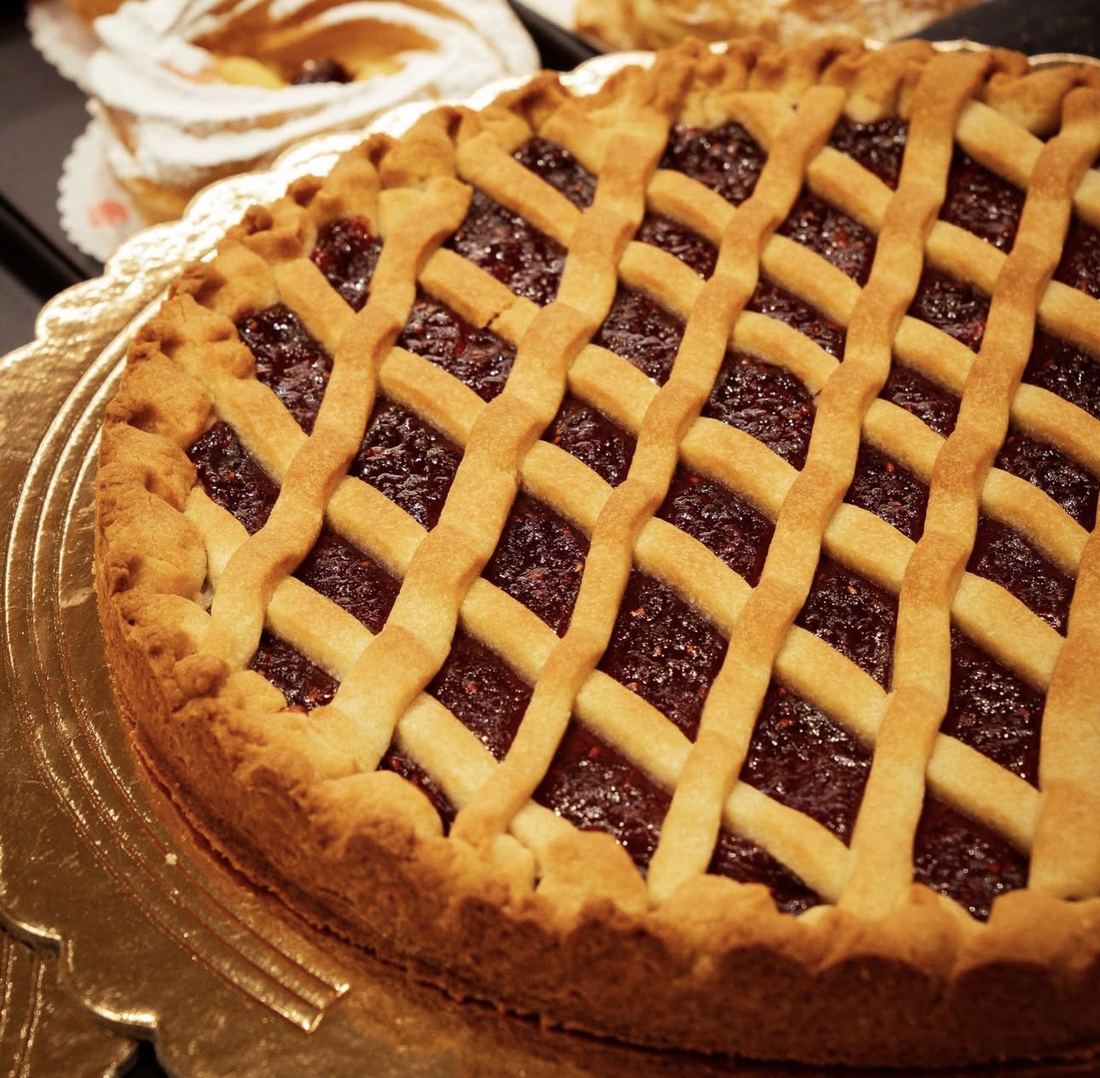 Crostata con confettura e griglia di frolla su un vassoio dorato