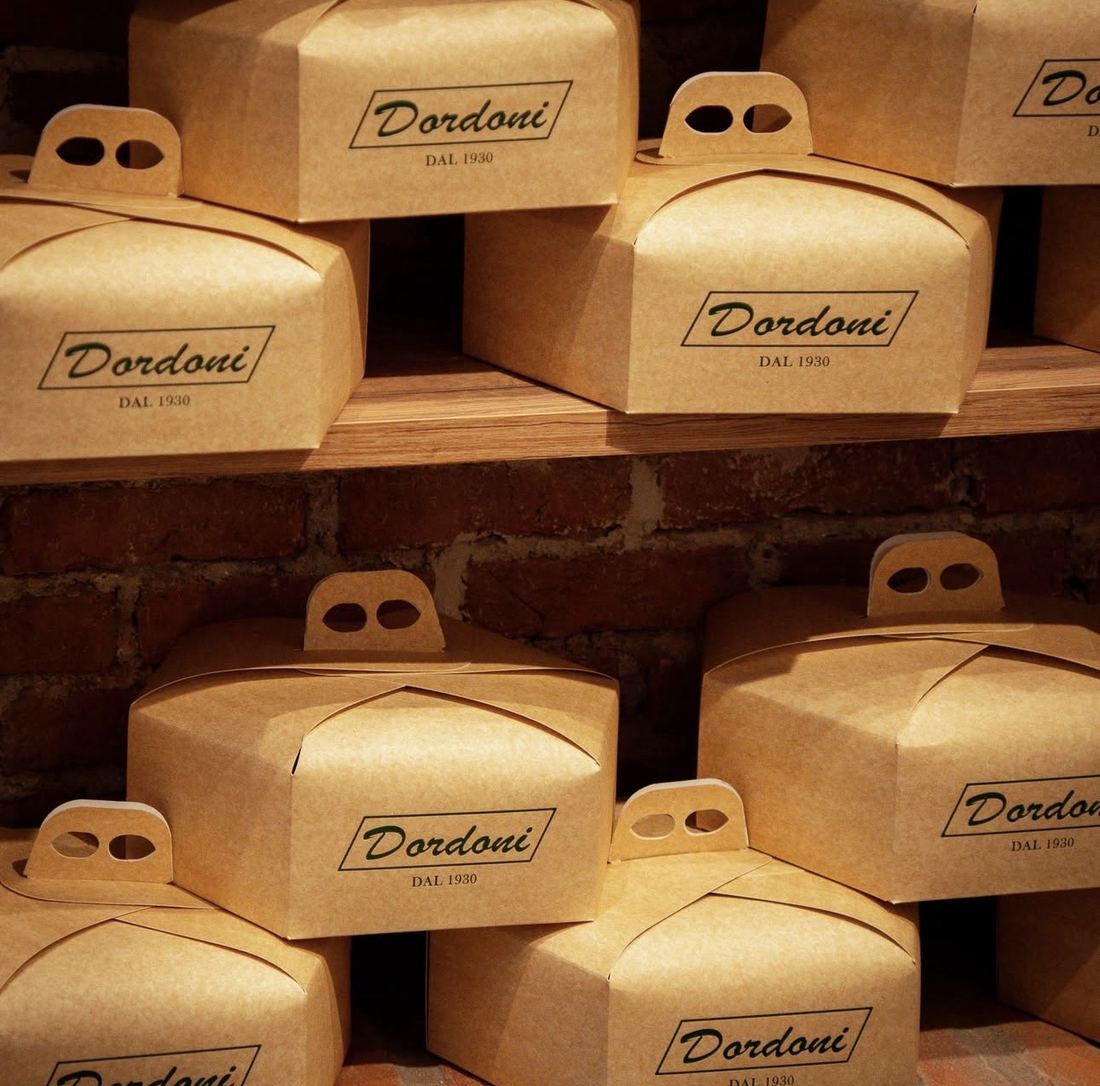 Pile di scatole di cartone Dordoni dal 1930 su una mensola di legno davanti a un muro di mattoni