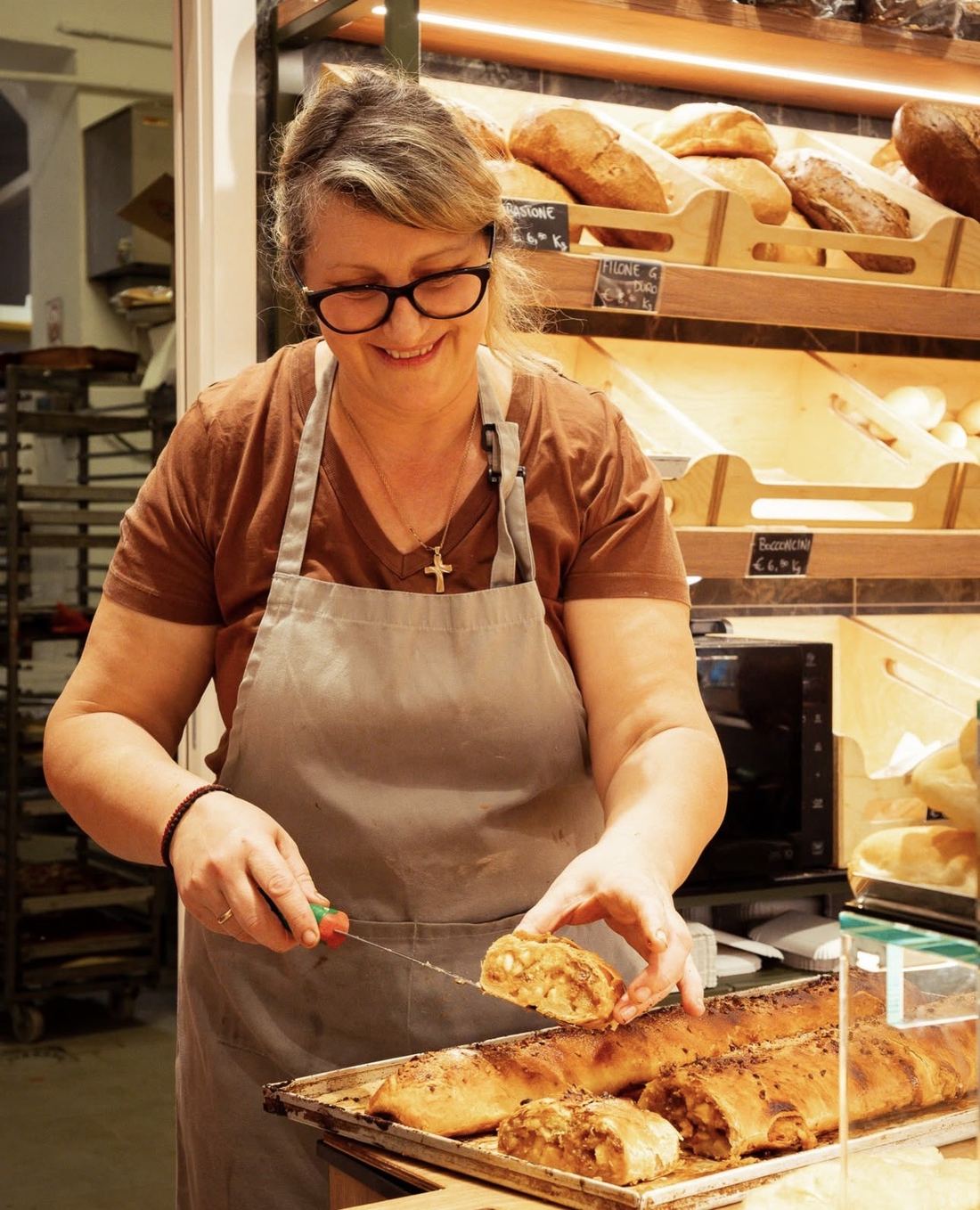 Una delle titolari di Dordoni, sorridente al banco mentre taglia una fetta di strudel